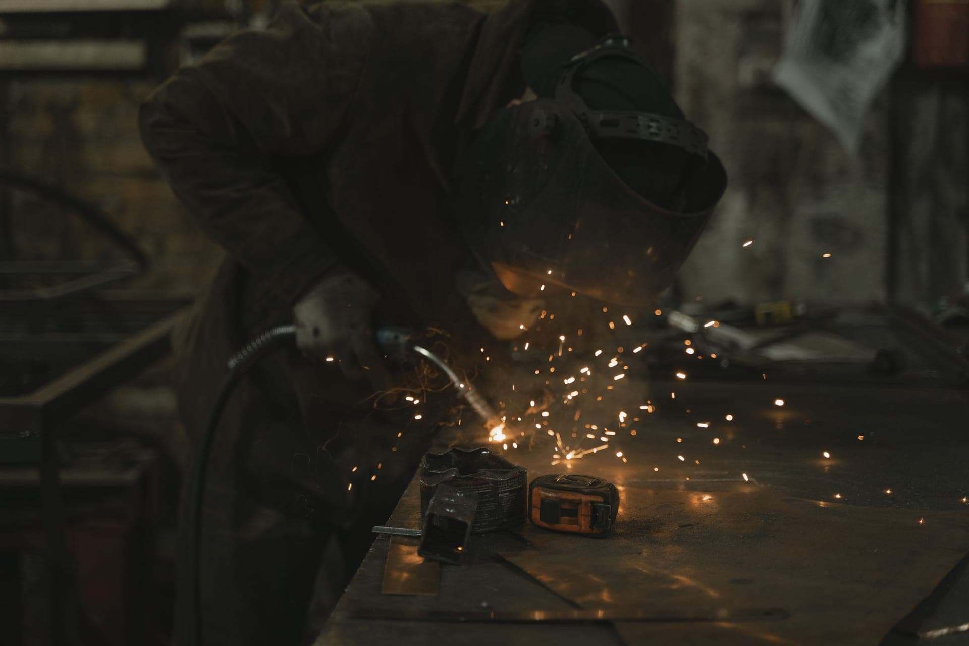 A person welding a steel joint in a bright workshop
