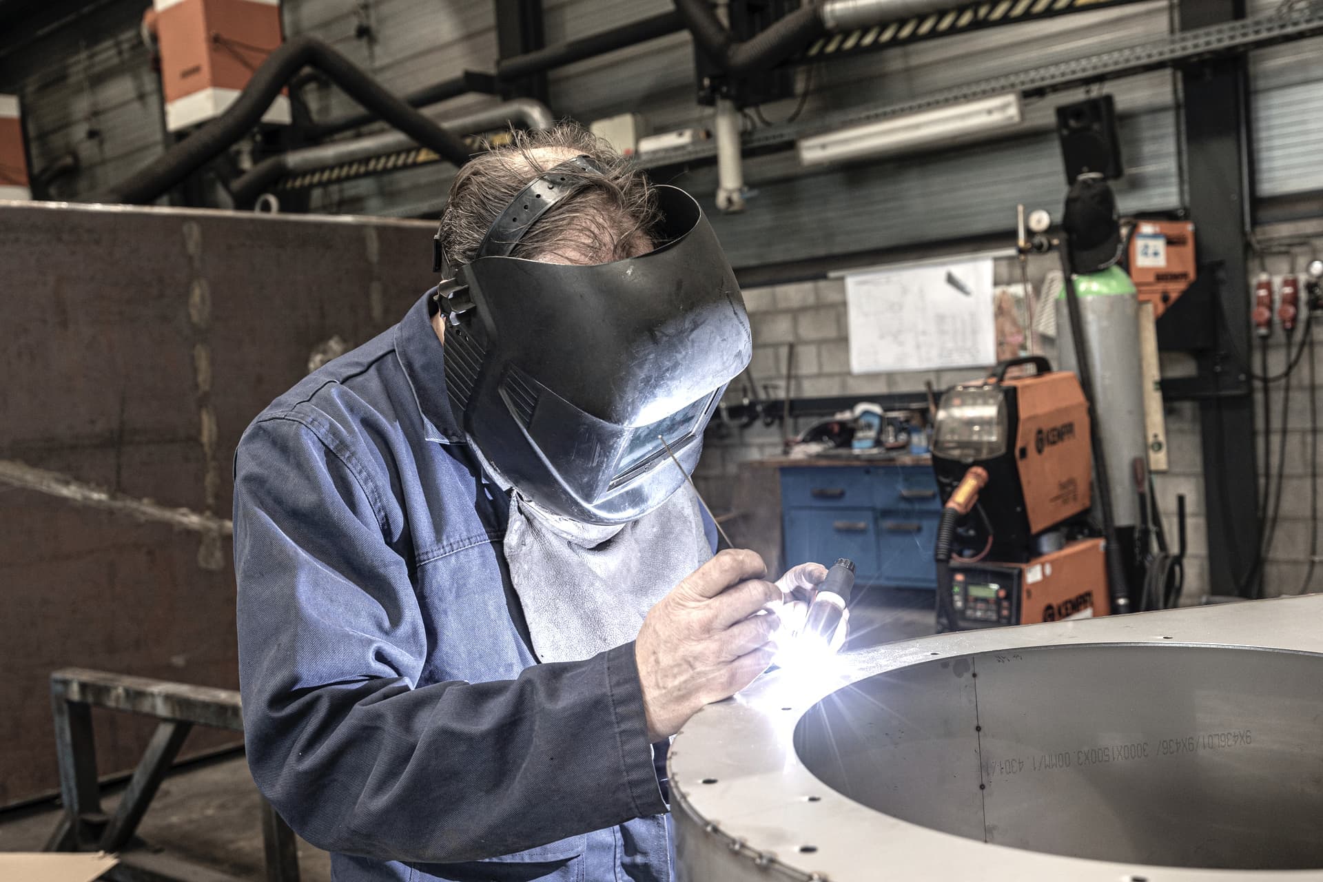 A gas-capable MIG welding machine beside a shielding gas cylinder in a workshop