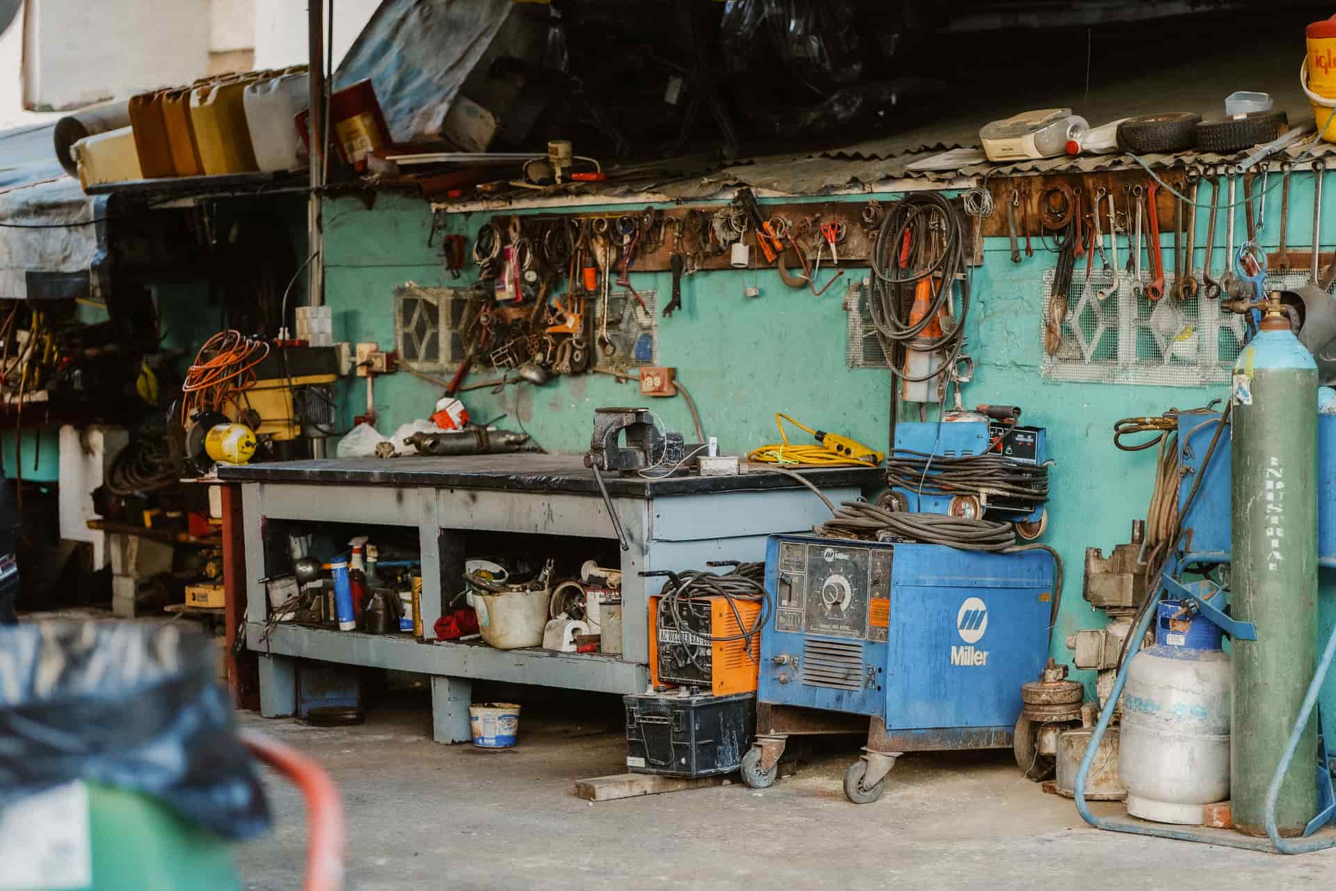 A compact flux-core wire-feed welder standing on a wooden workbench in daylight