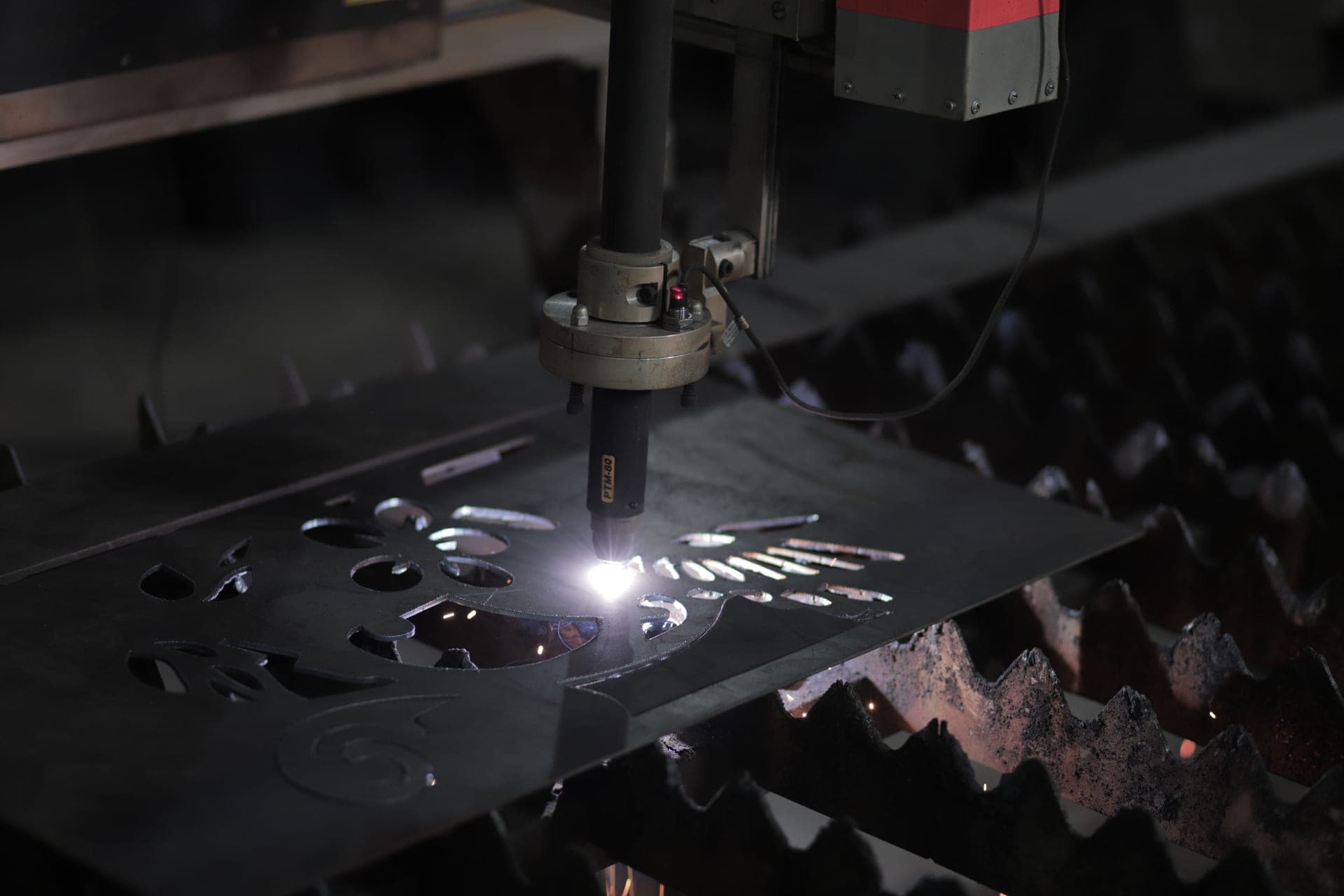A 50 amp plasma cutter with an air line attached, standing next to freshly cut steel plate